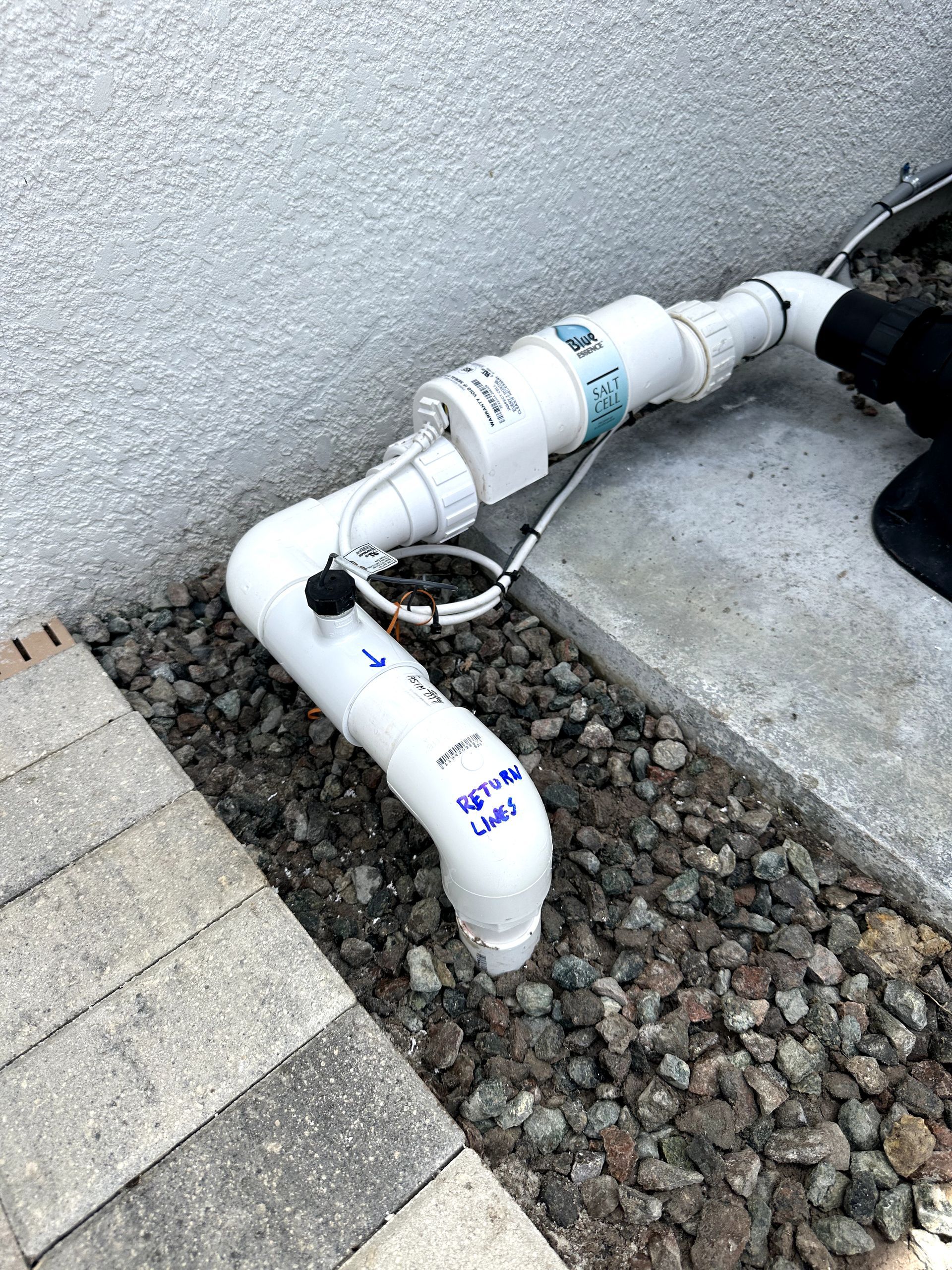 A white pipe is sitting on top of a pile of rocks next to a wall.