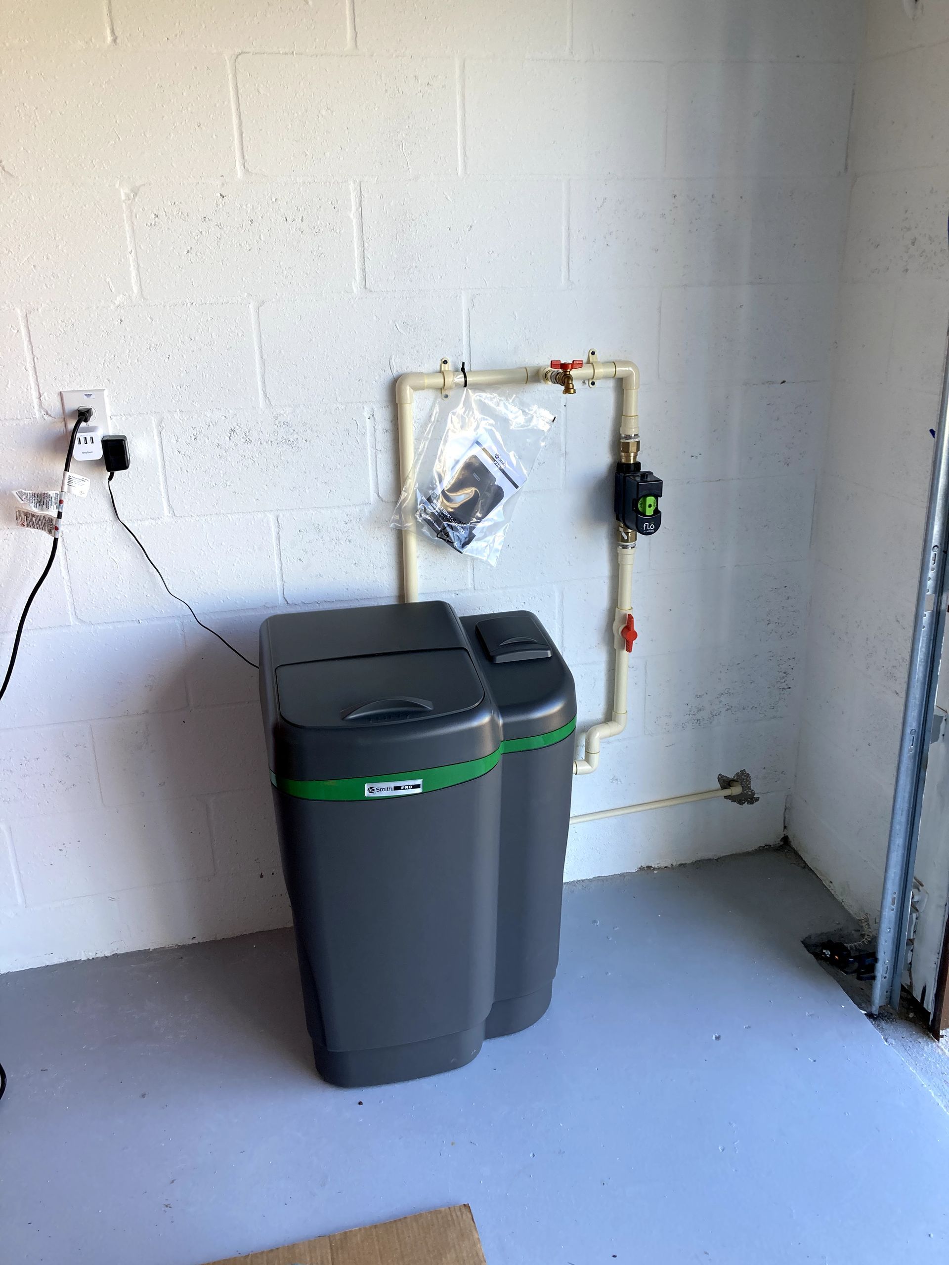 A water softener is sitting in a room next to a brick wall.