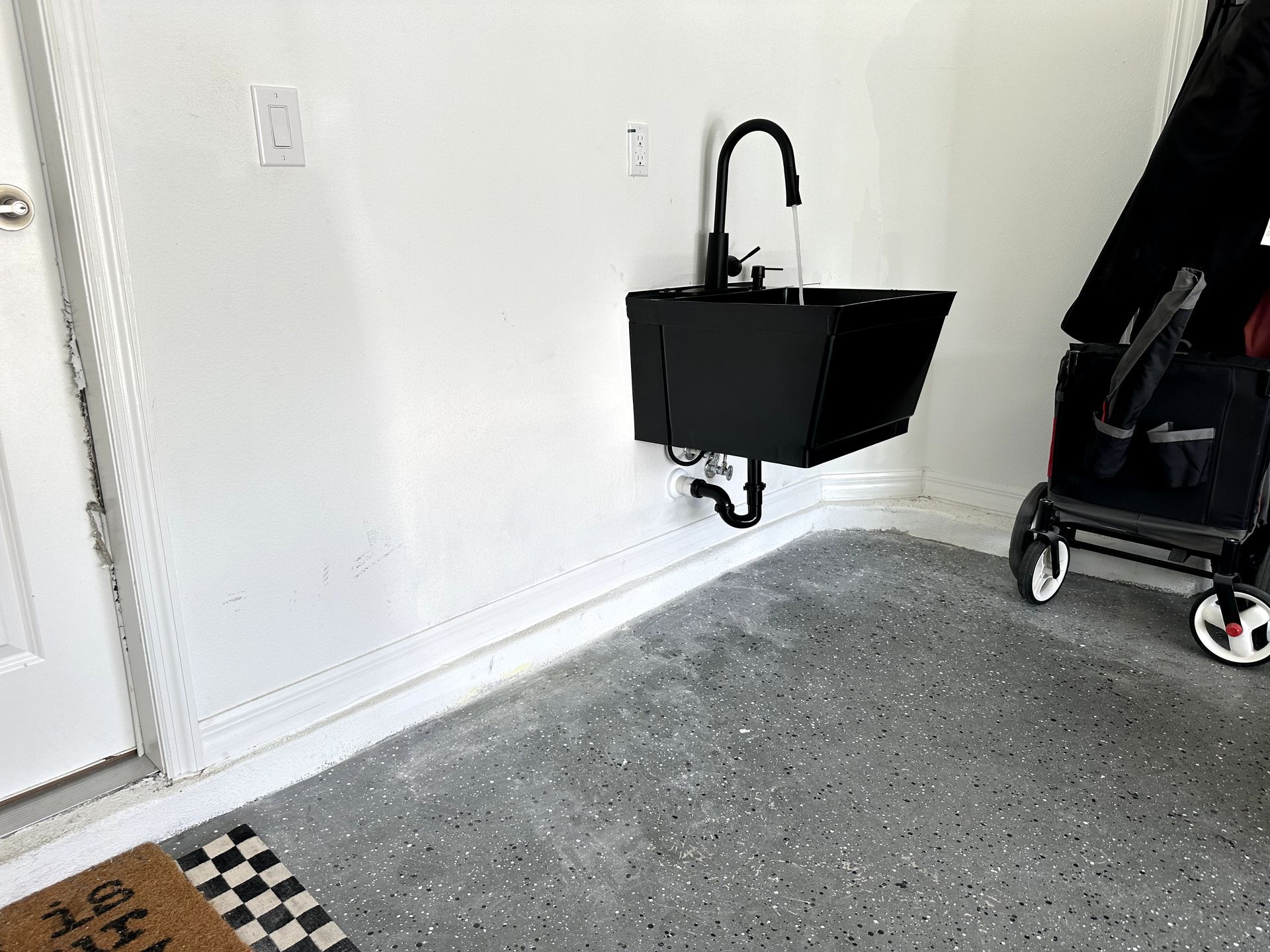 A person is pushing a stroller in a garage next to a sink.