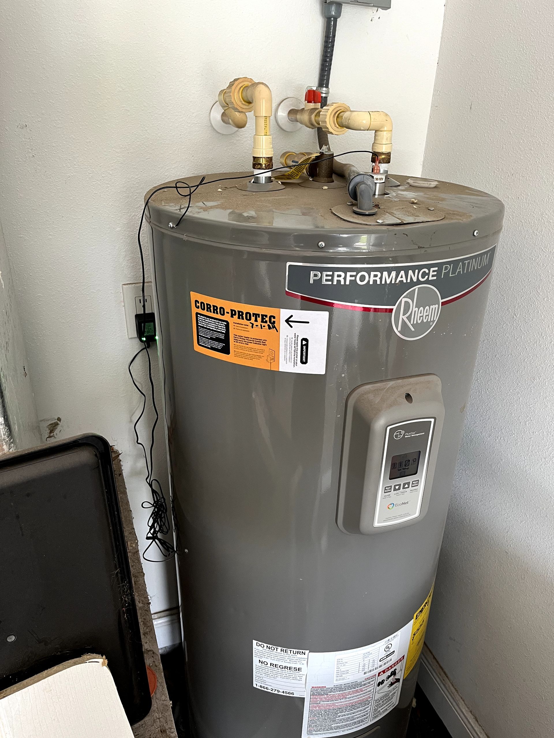 A gray water heater is sitting in a corner of a room.