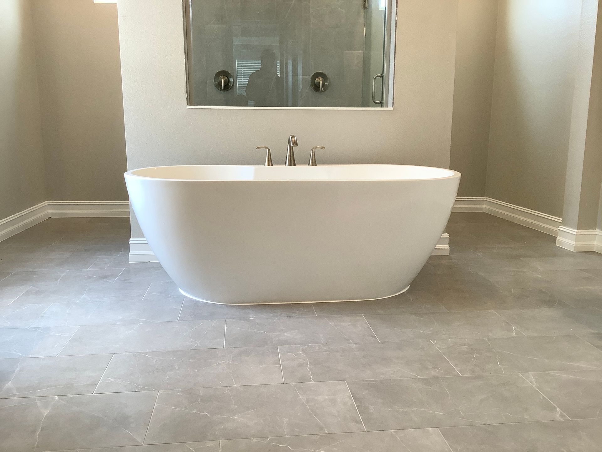 A white bathtub is sitting on a tiled floor in a bathroom.