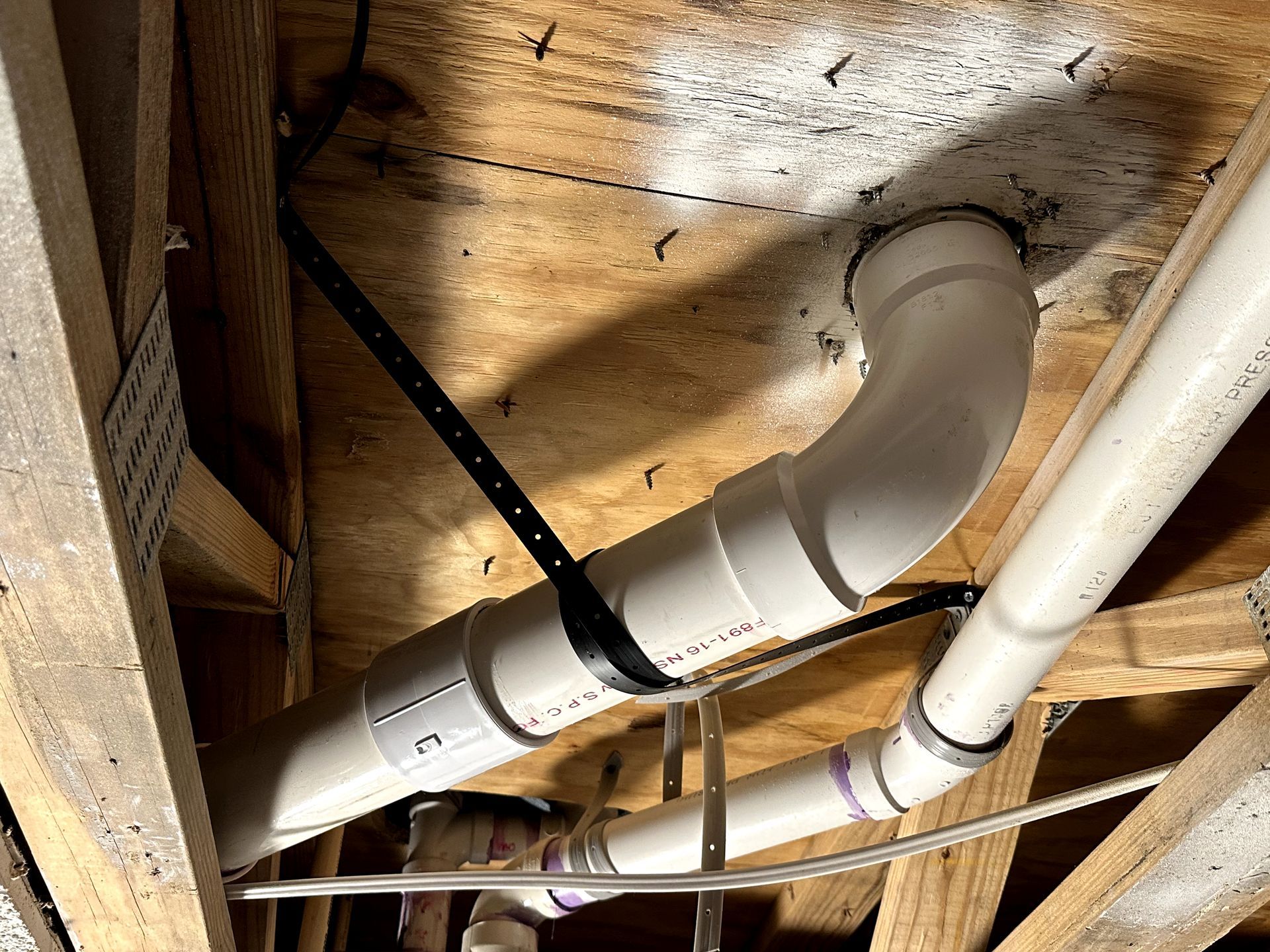 A bunch of pipes are hanging from the ceiling of a building.