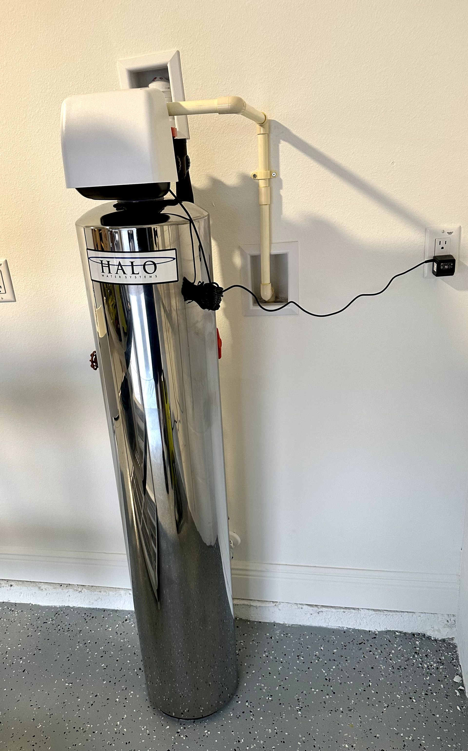 A stainless steel water filter is attached to a wall.