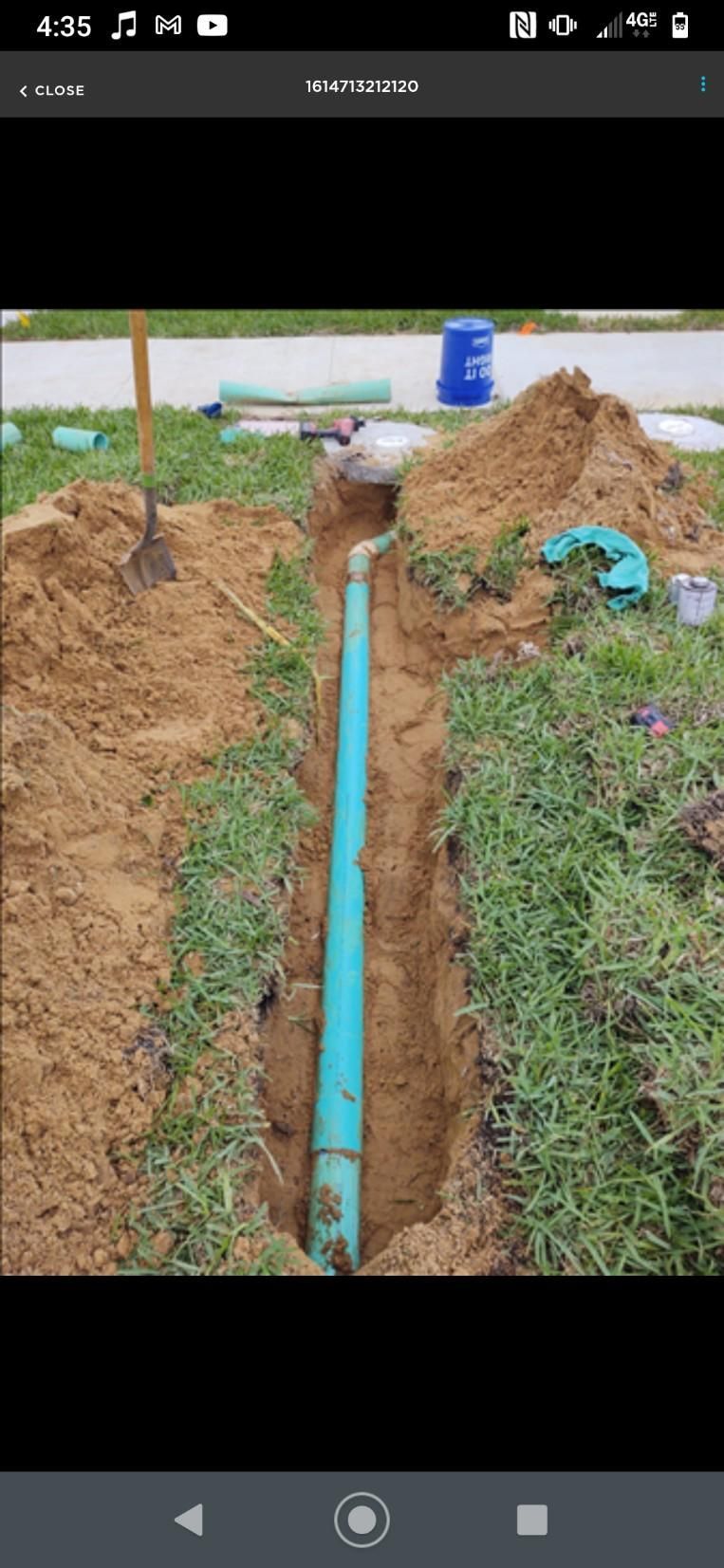 A blue pipe is being installed in a hole in the ground.