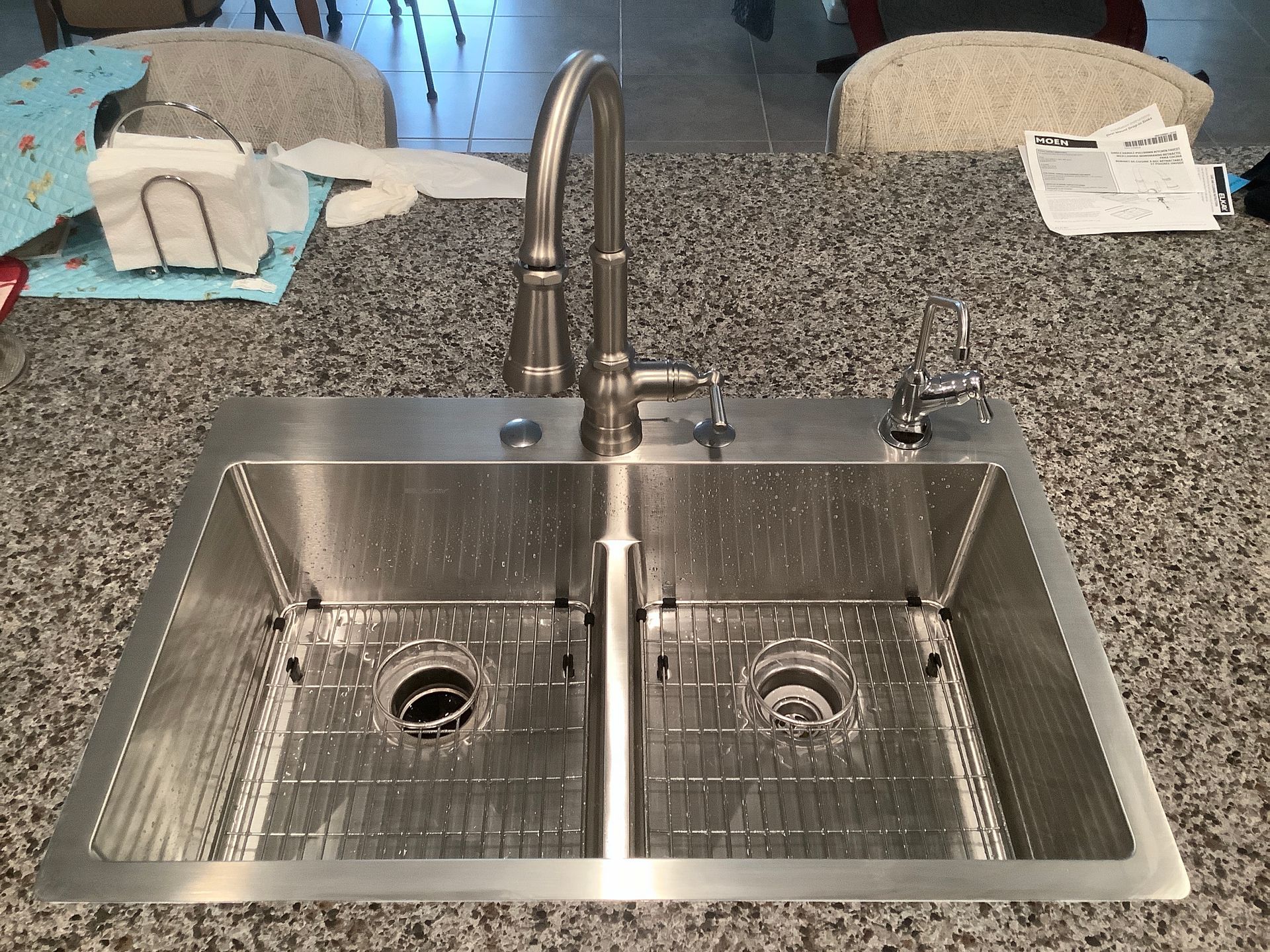A stainless steel kitchen sink is on a granite counter top
