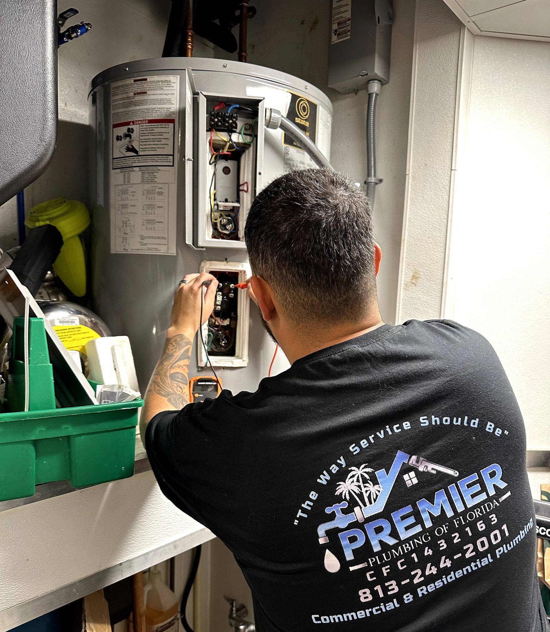 A man is working on a water heater in a kitchen.