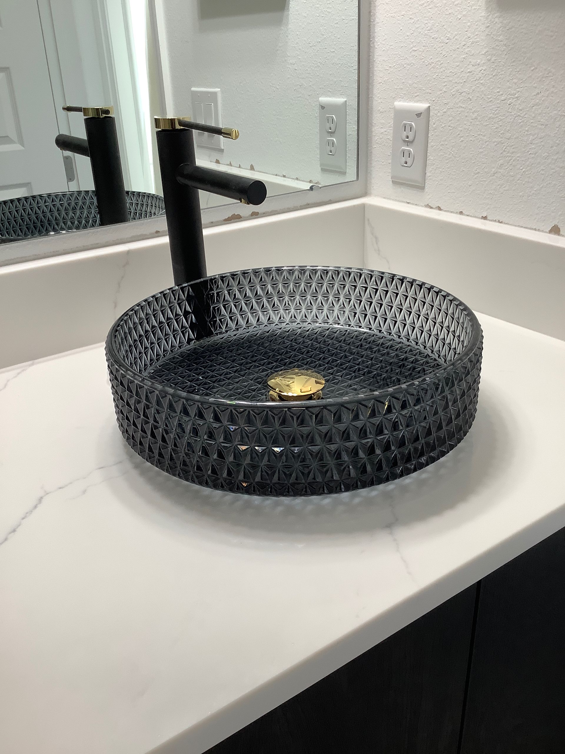 A bathroom sink with a black faucet and a mirror.