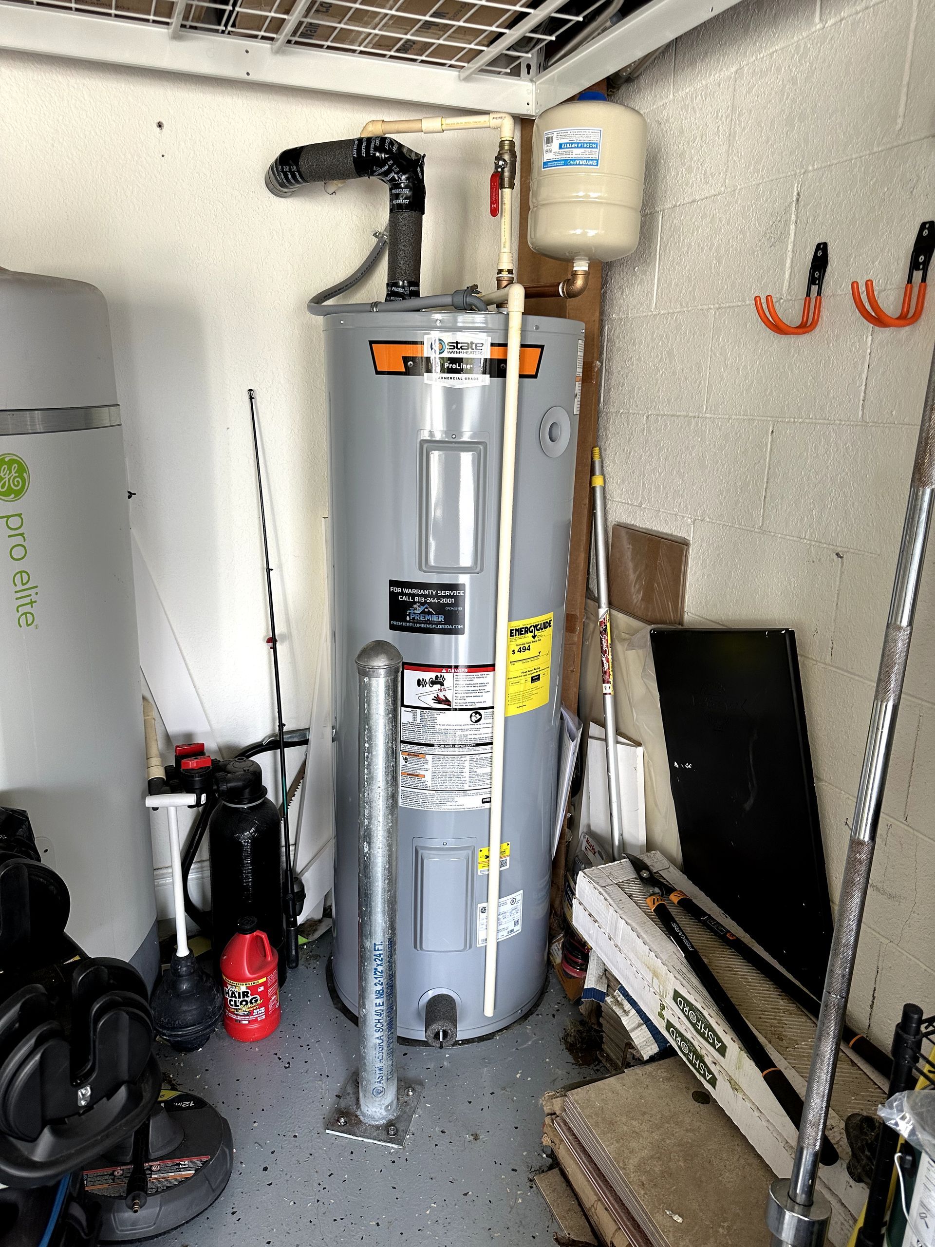 A water heater is sitting in a garage next to a wall.