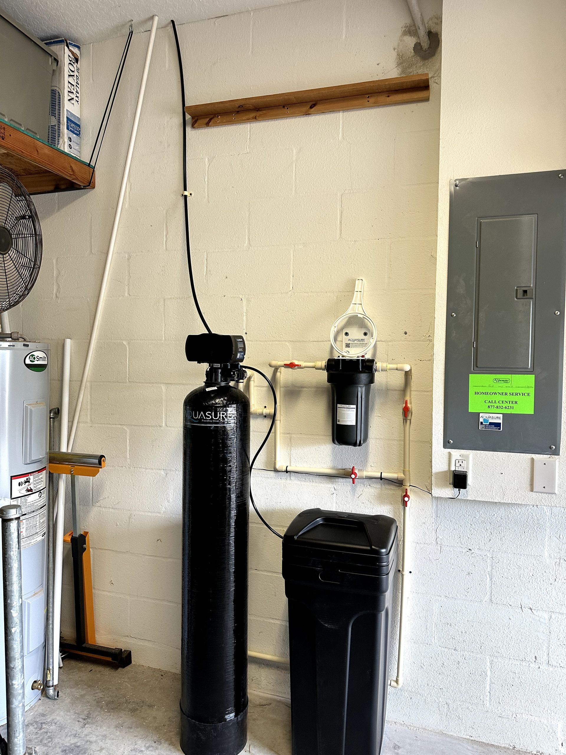 A black water filter is sitting next to a black tank in a room.