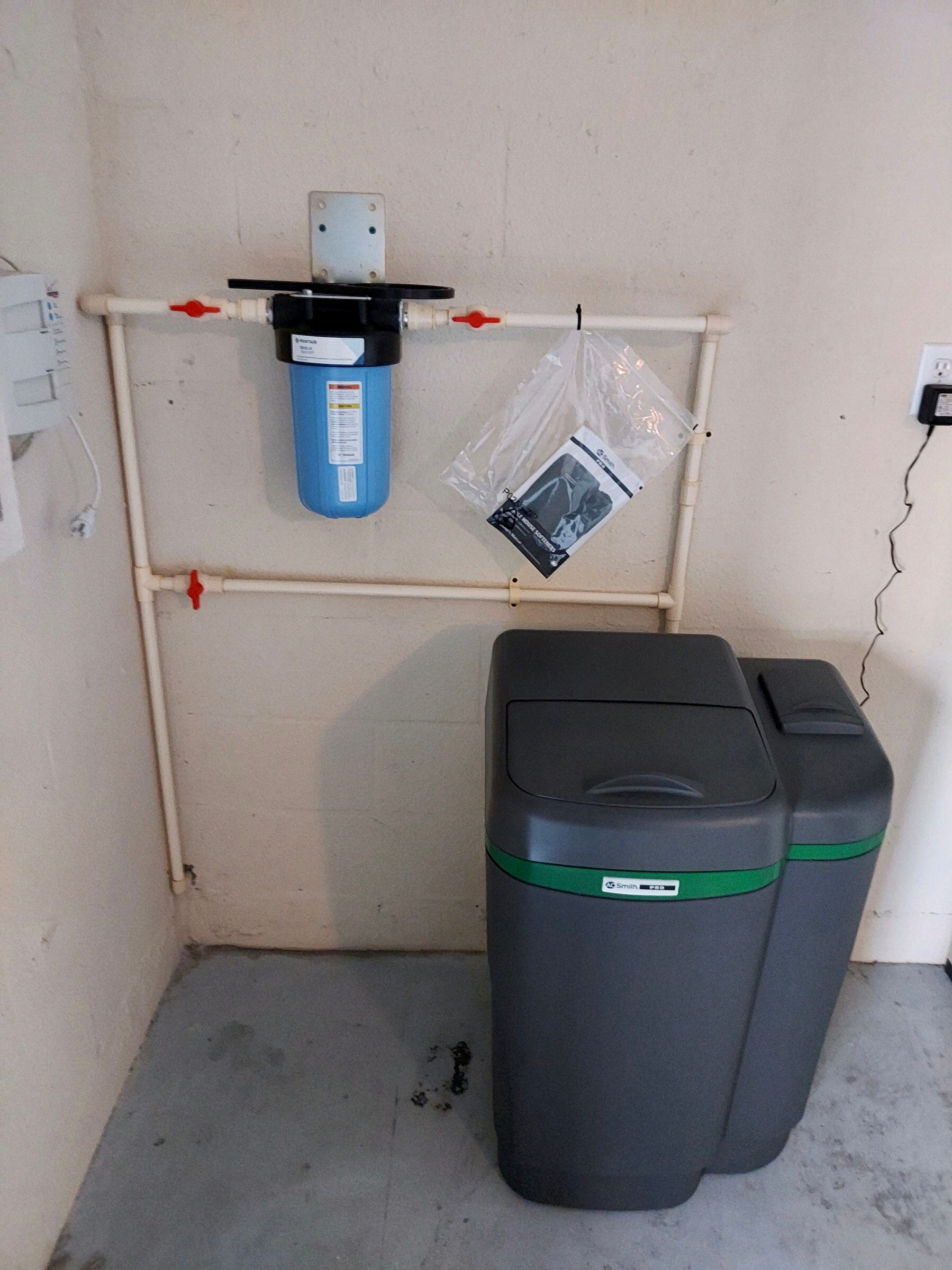 A water softener is sitting in a room next to a wall.