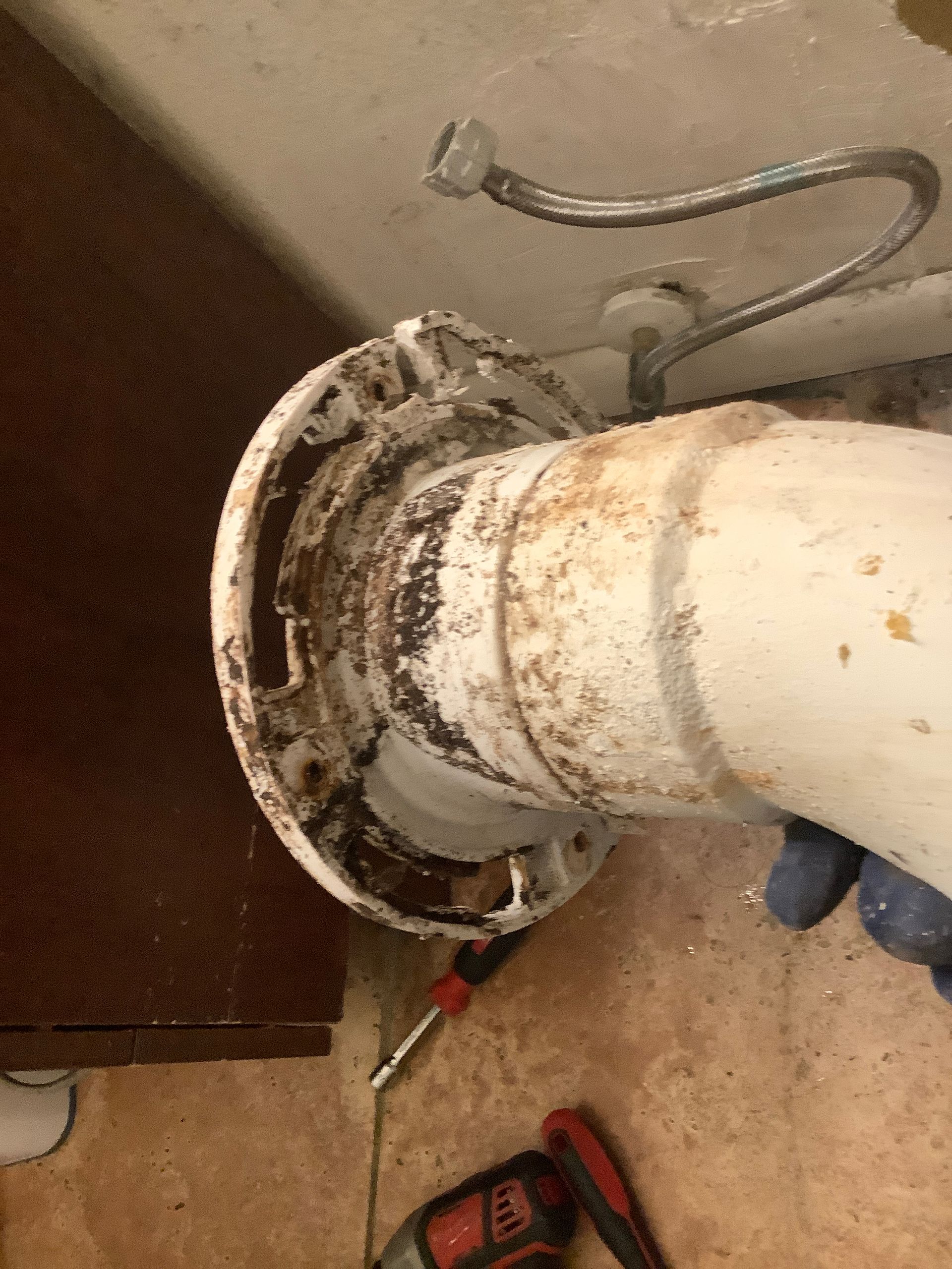 A person is fixing a toilet with a screwdriver.