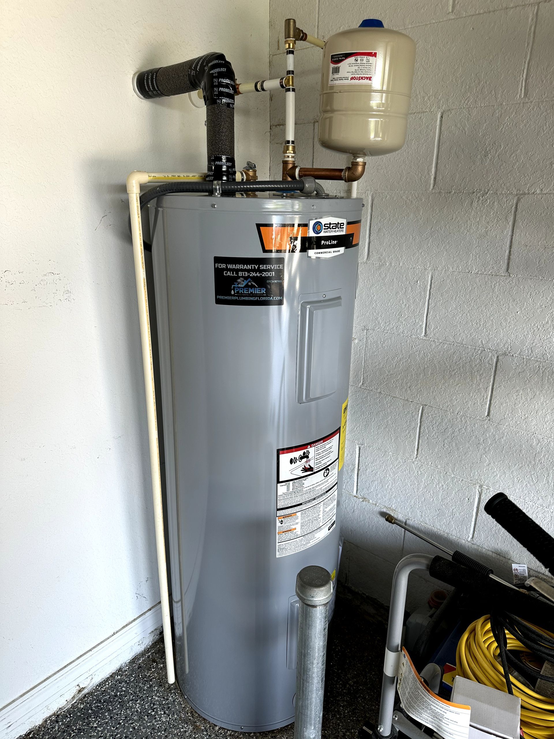 A water heater is sitting in a corner of a room next to a wall.