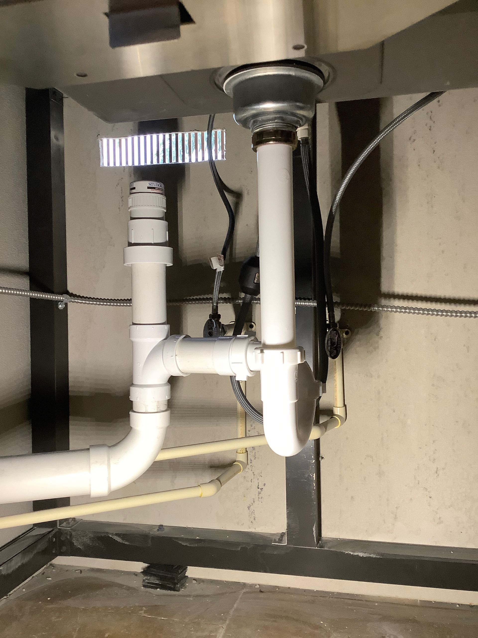 A sink with a lot of pipes underneath it