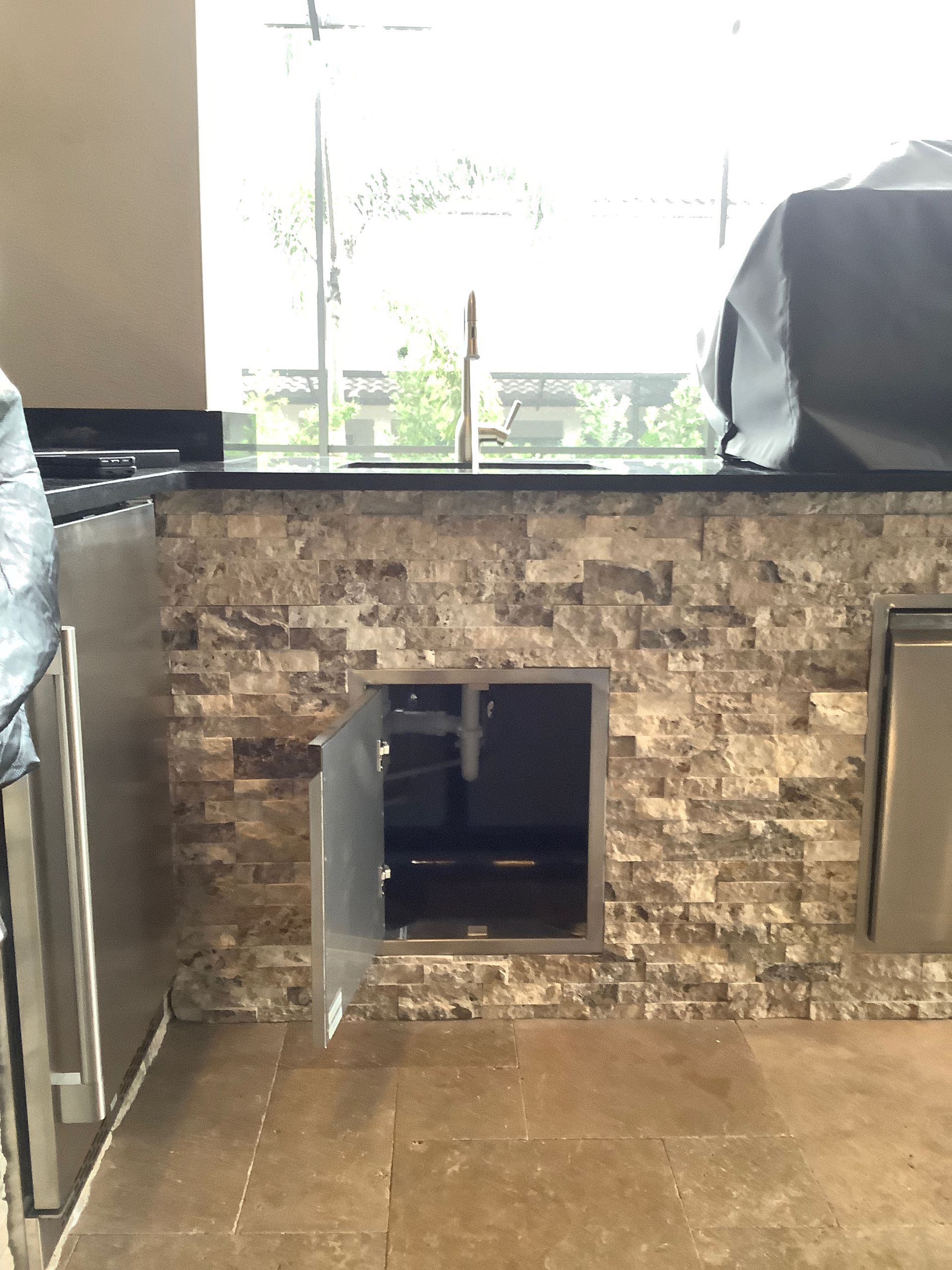 A kitchen with a brick wall and a stainless steel refrigerator