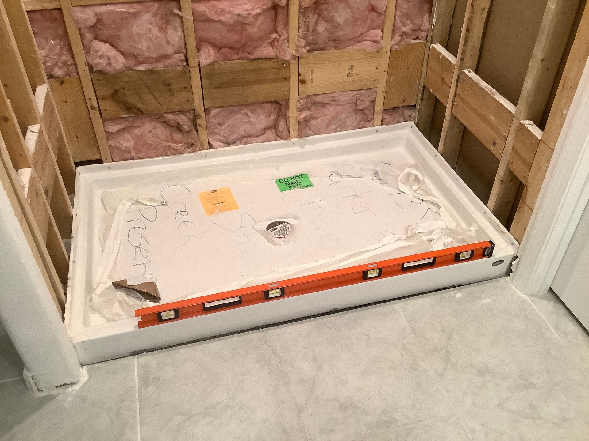 A shower stall is being built in a bathroom with a level on the floor.