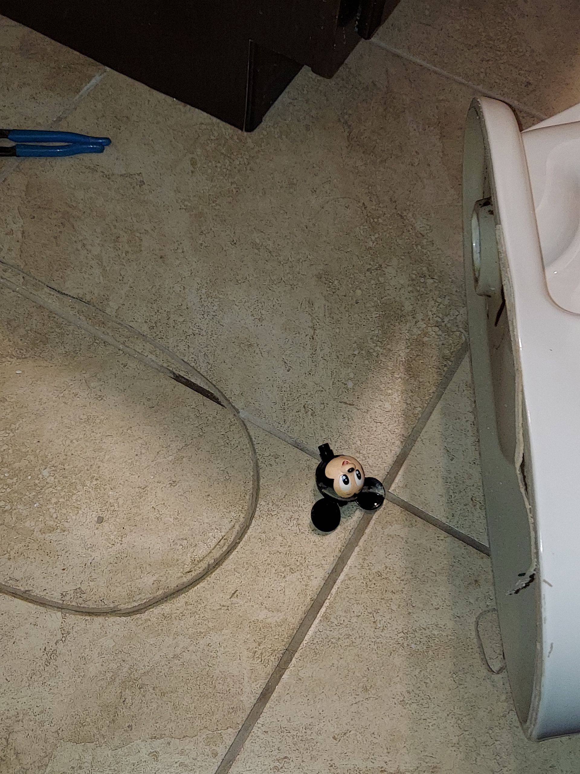 A stuffed animal is sitting on the floor next to a toilet.