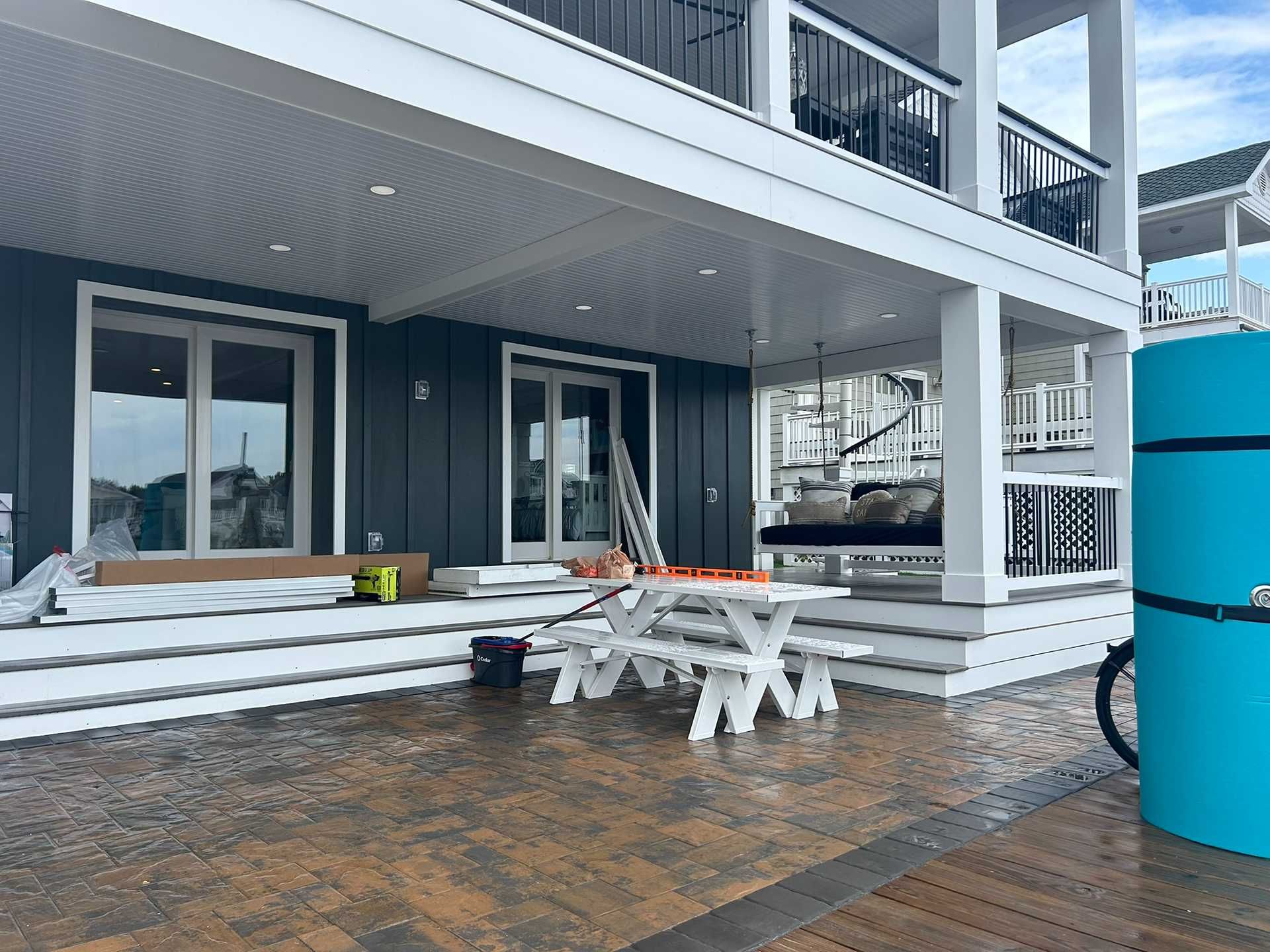 Exterior of a home with a porch, white trim, and gray siding. A picnic table and swing are visible.