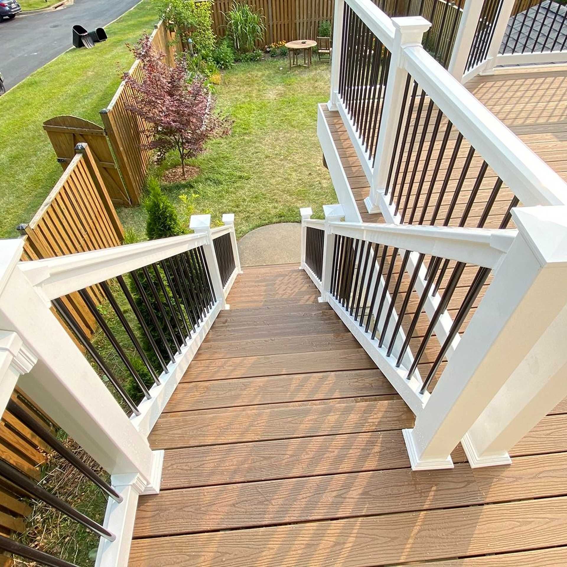 Wooden deck with white railings and black spindles, leading down to a grassy yard.