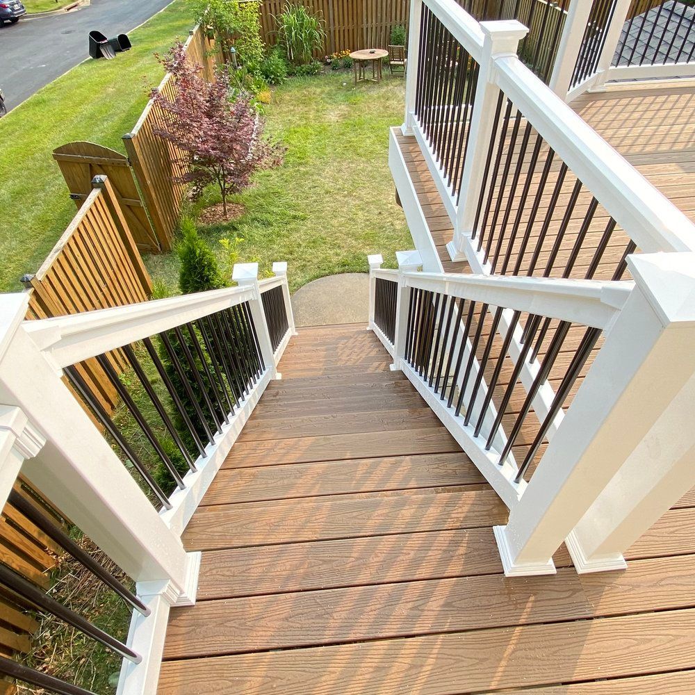 Wooden deck stairs with white railings and black balusters leading down to a grassy yard.