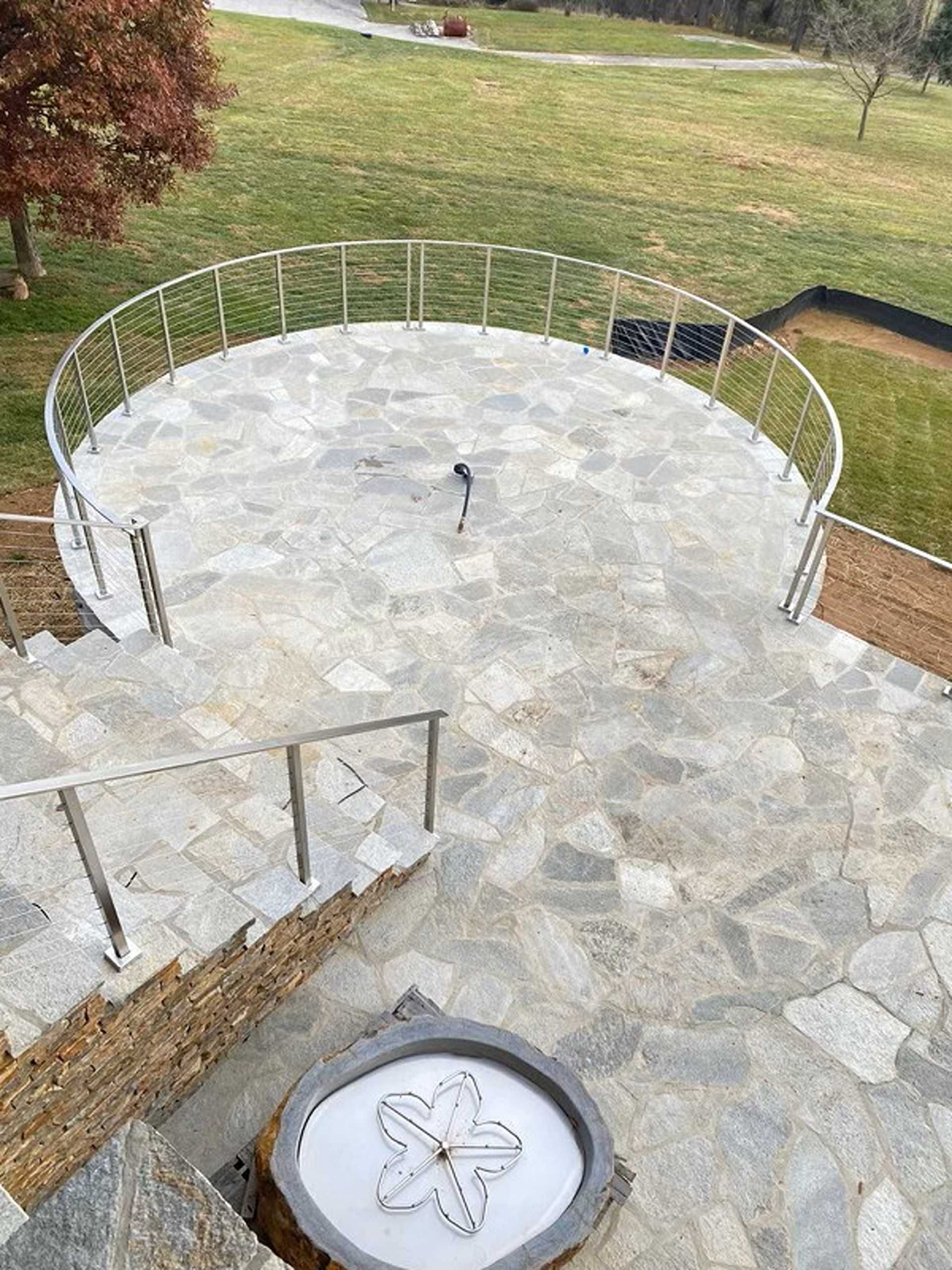 Stone patio with metal railing and stairs leading down.
