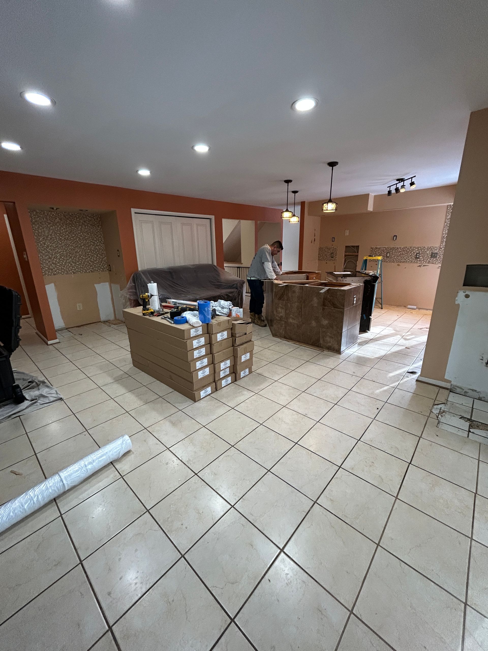 Interior undergoing renovation with stacked boxes, a person, and a partially constructed island.