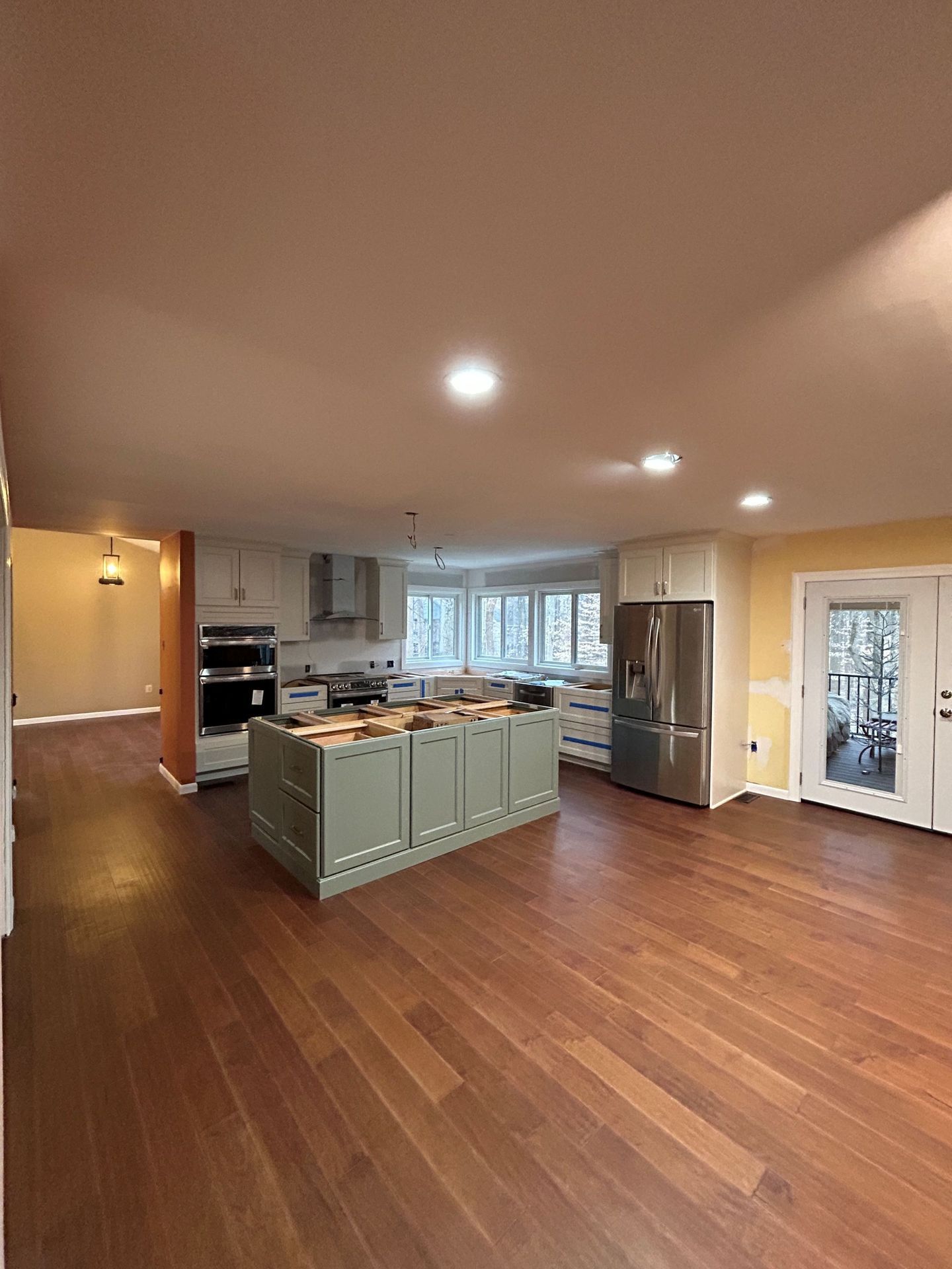 Spacious kitchen with wood floors, island, stainless steel appliances, and large windows.