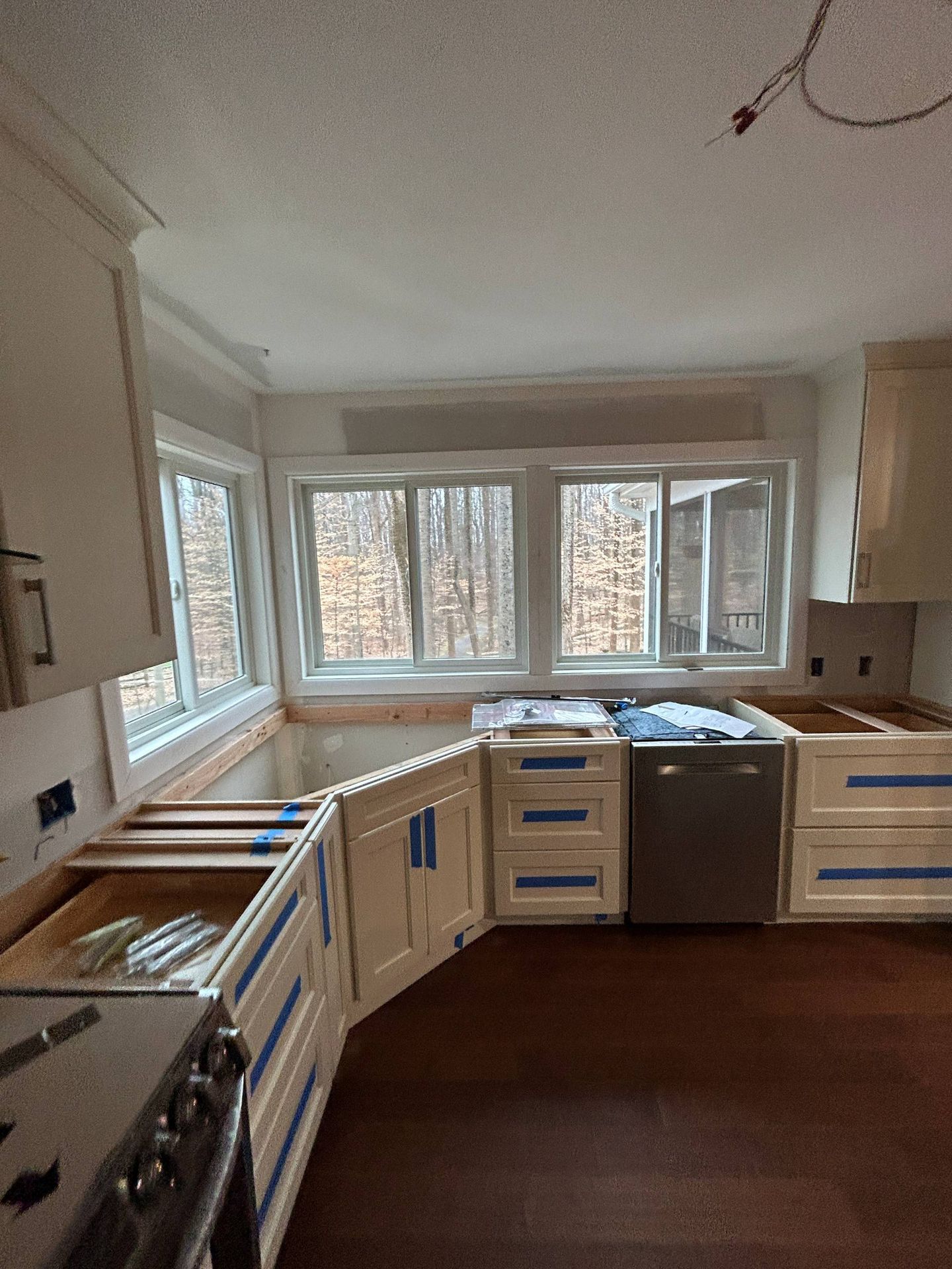 Kitchen cabinets being installed around windows and appliances.