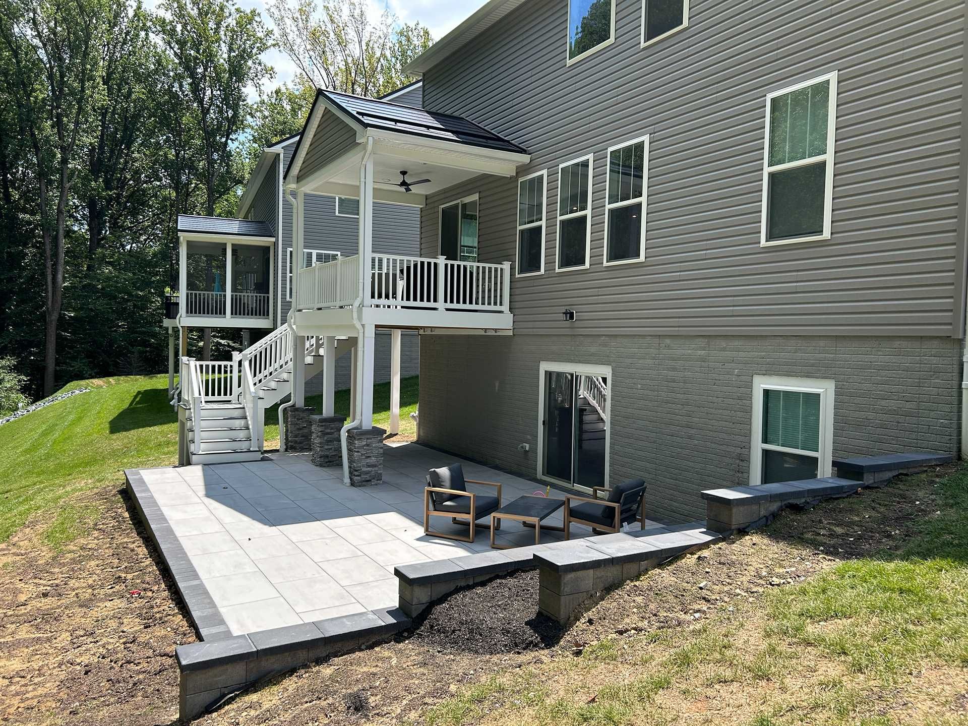 A two-story home with a patio and deck overlooking a grassy yard.
