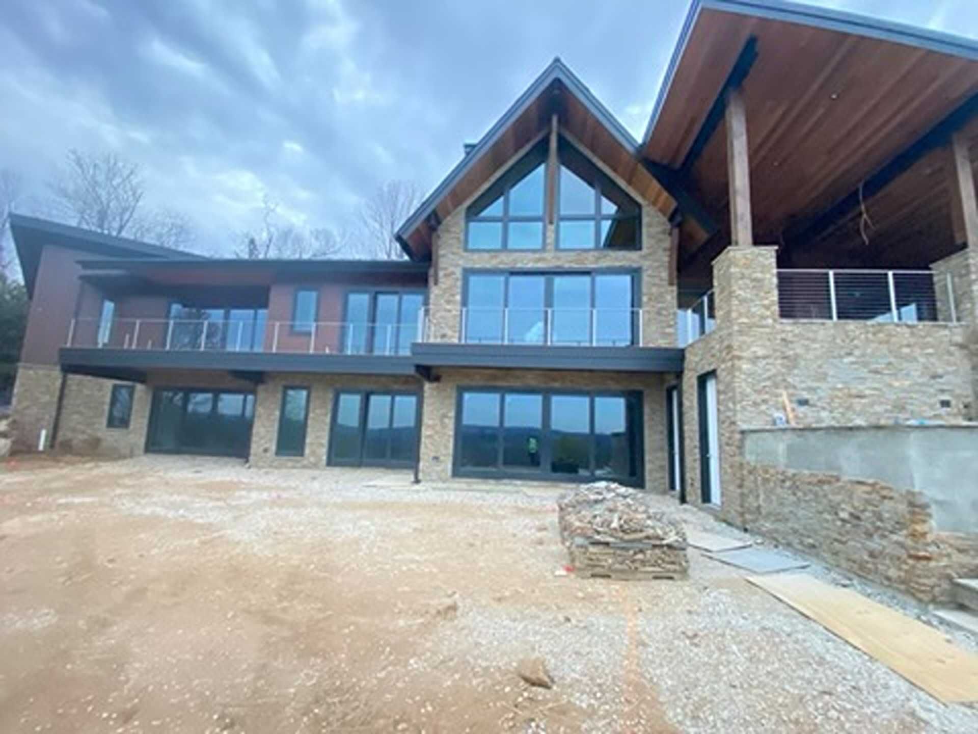 Large modern house with stone and glass facade, under a cloudy sky.