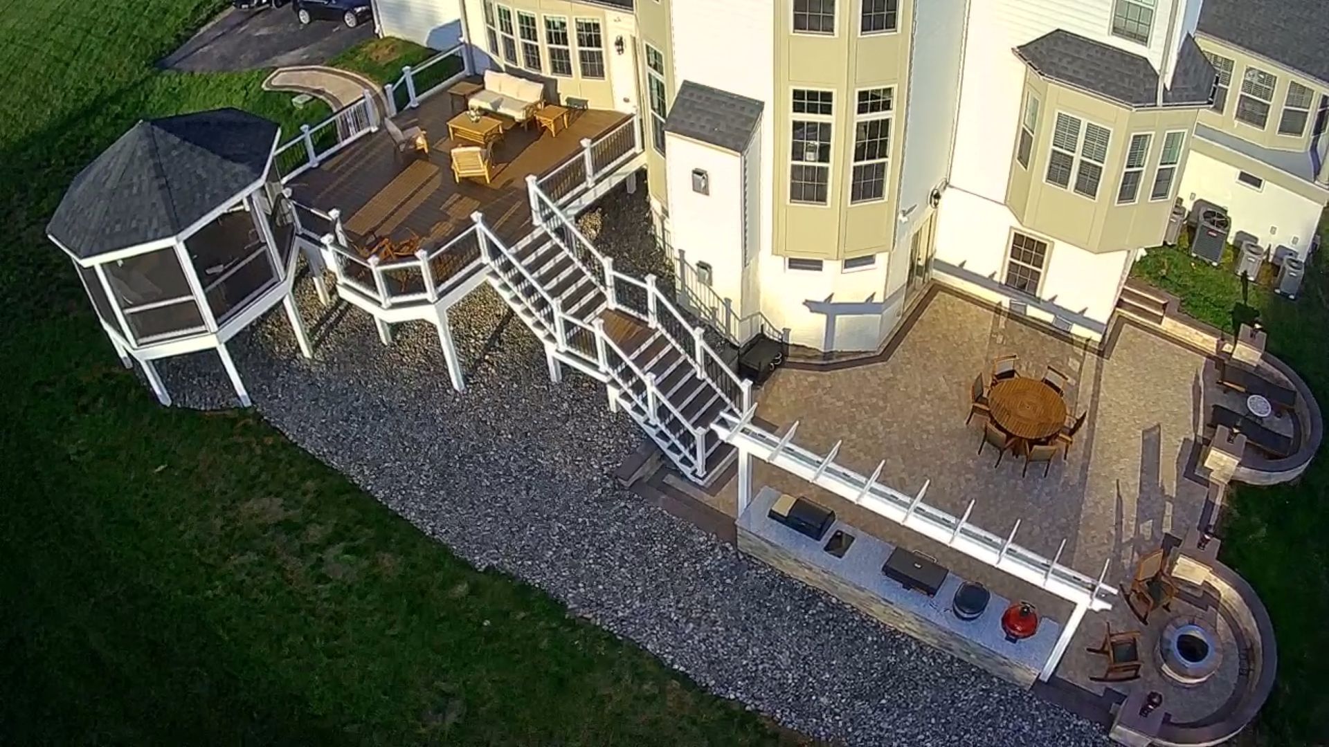 Aerial view of a multi-level deck and patio connected to a large house, with outdoor furniture and a gazebo.