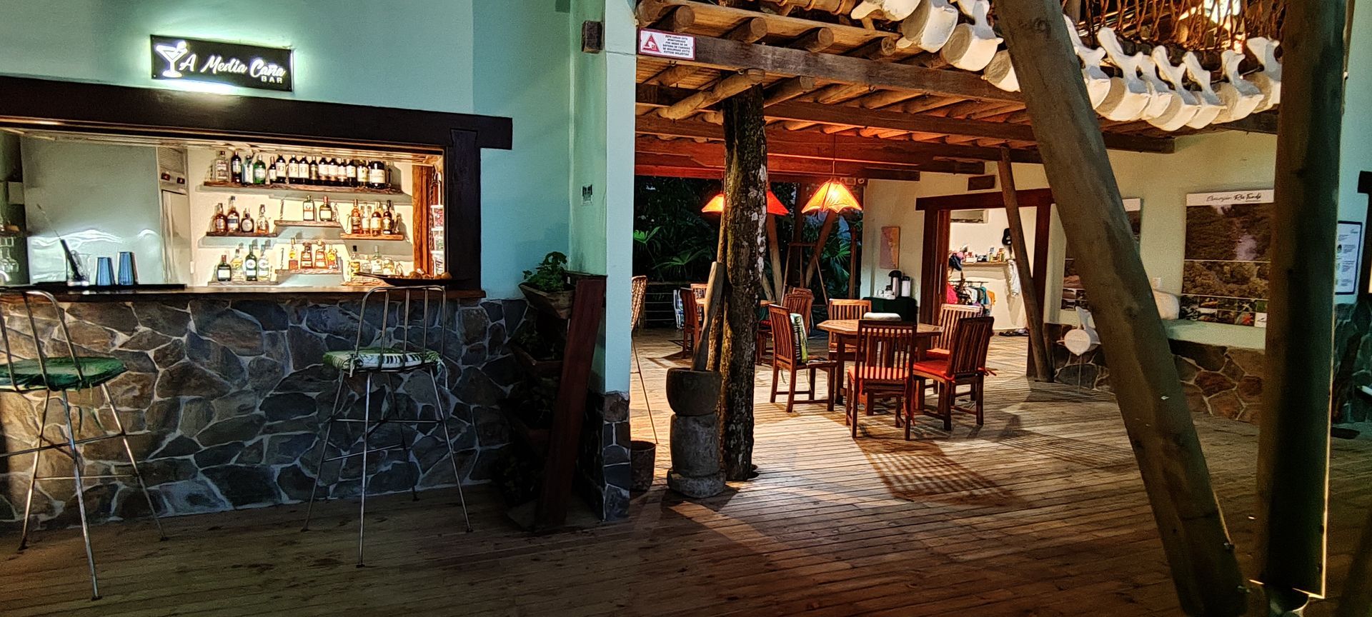 Dimly lit rustic restaurant interior with stone walls, wooden beams, and cozy seating.