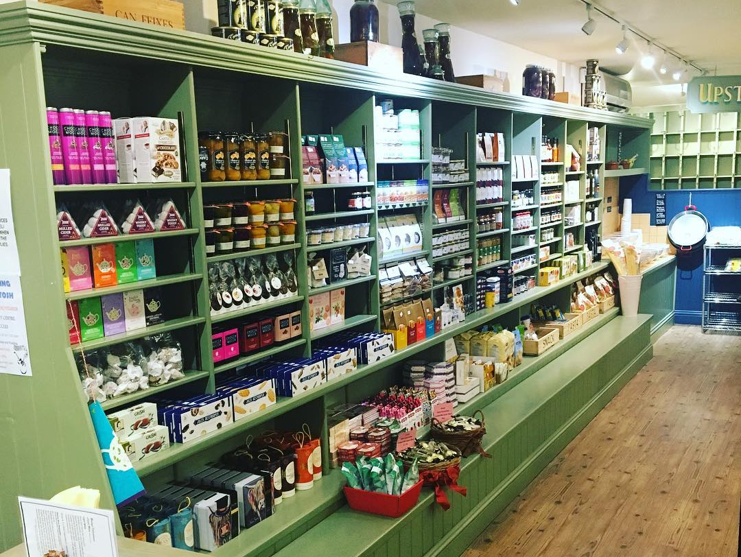 shop aisle with goods for sale on green shelves