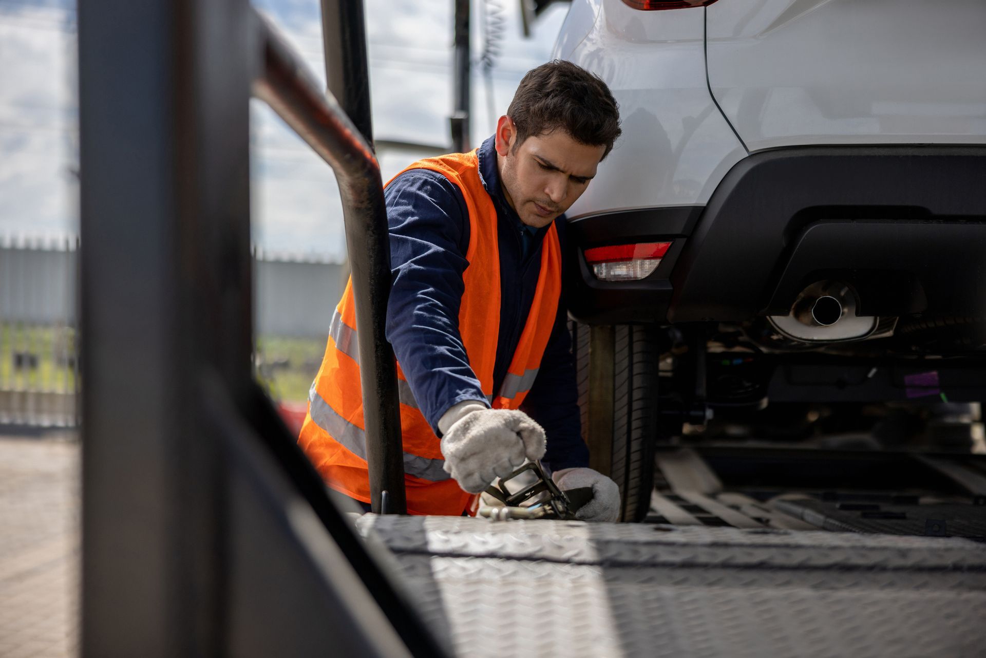 A man is working on a car on a tow truck.