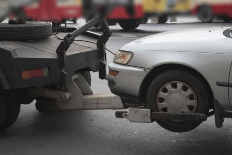 A trailer is being towed by a truck on a road.