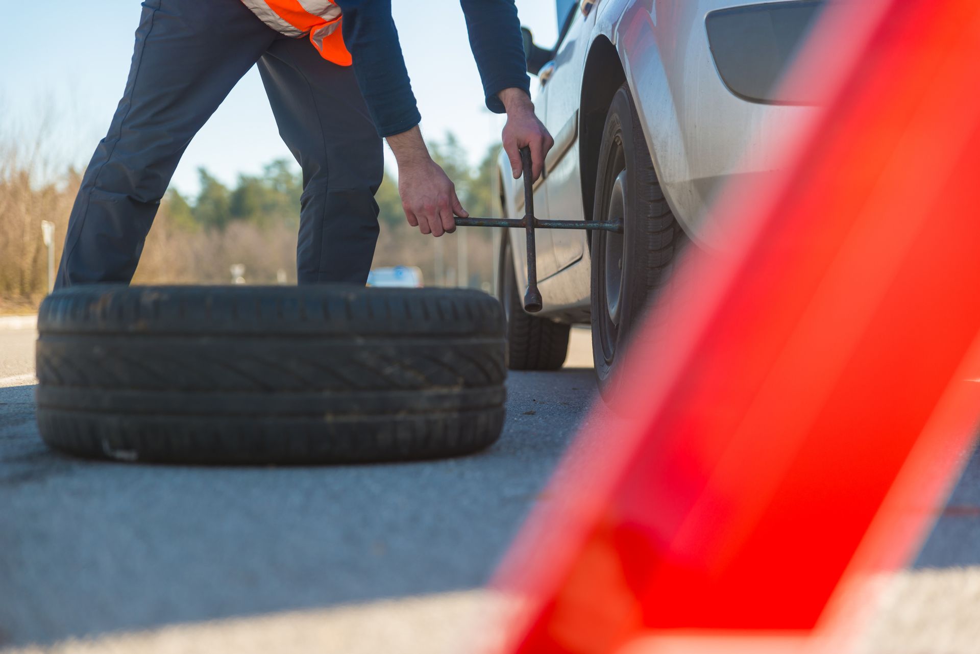 A man is changing a tire on the side of the road.