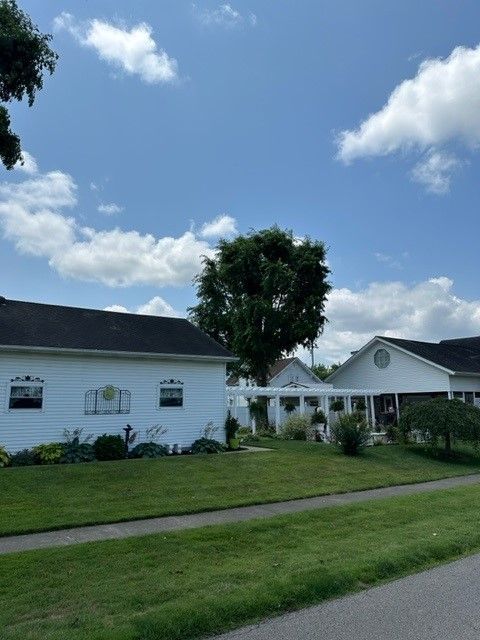 A white house with a black roof sits on a lush green lawn