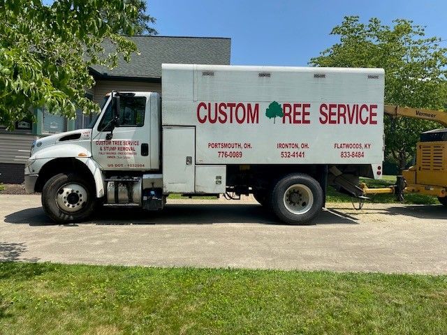 A white truck that says custom ree service is parked in a driveway