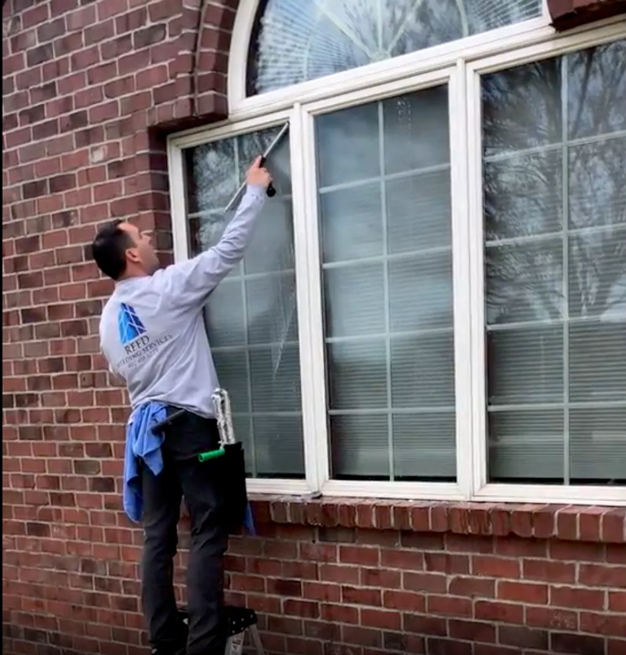 A man is cleaning a window on a brick building