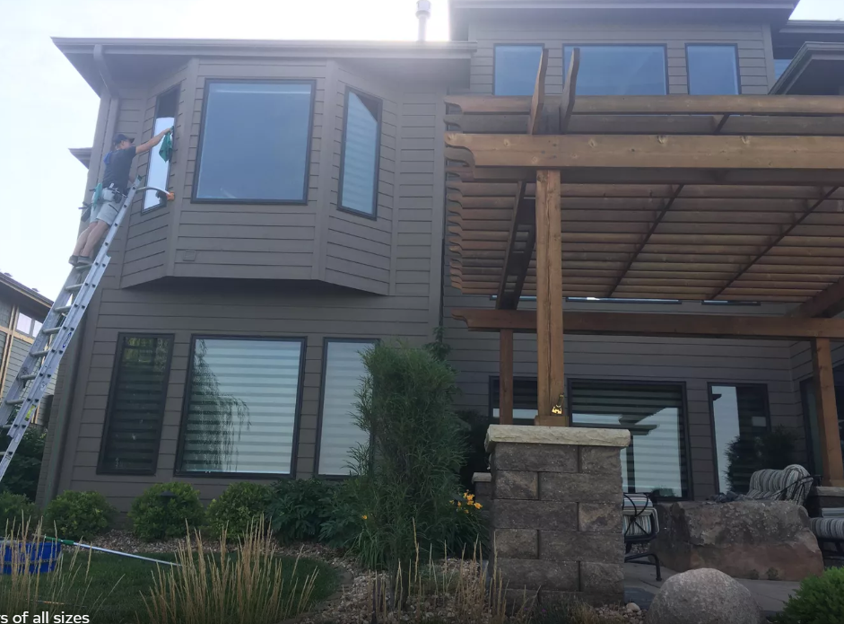 A man is cleaning the windows of a house with a ladder.