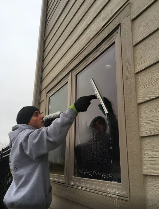 A man is cleaning a window with a squeegee.