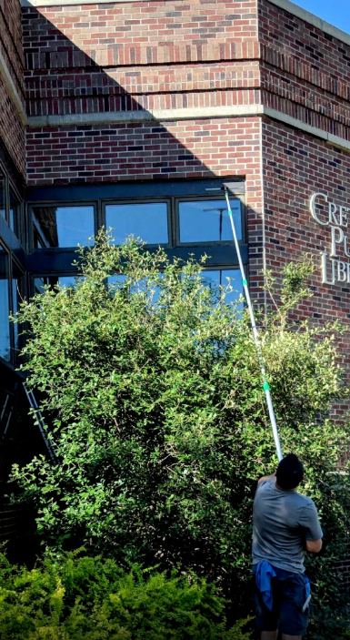 A man is cleaning the windows of a brick building.