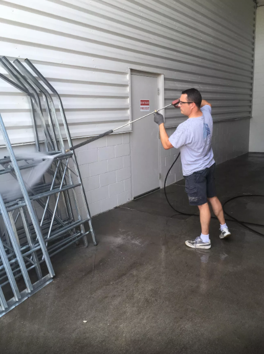 A man is cleaning a building with a hose.