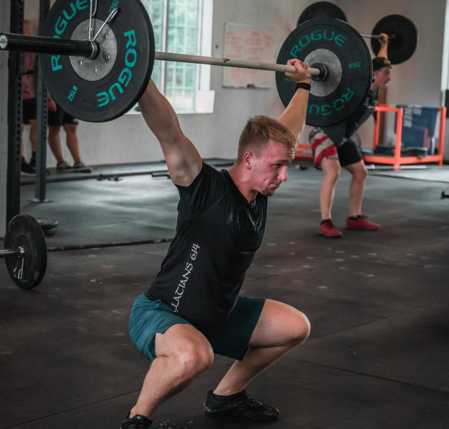 Man at Power and Fitness gym in Bloomington, IL doing a barbell overhead squat; lifting weight.