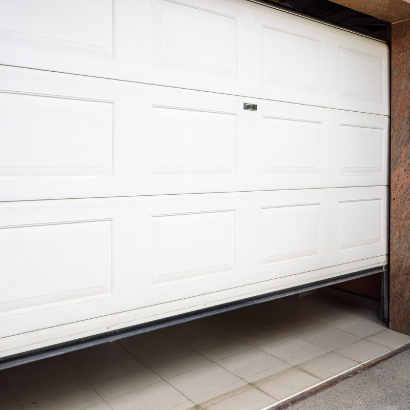 White garage door partially open, revealing a tiled floor.
