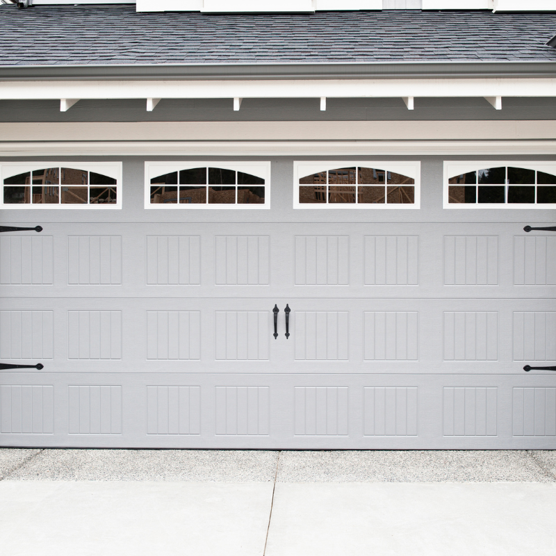 Gray garage door with four arched windows and black hardware.