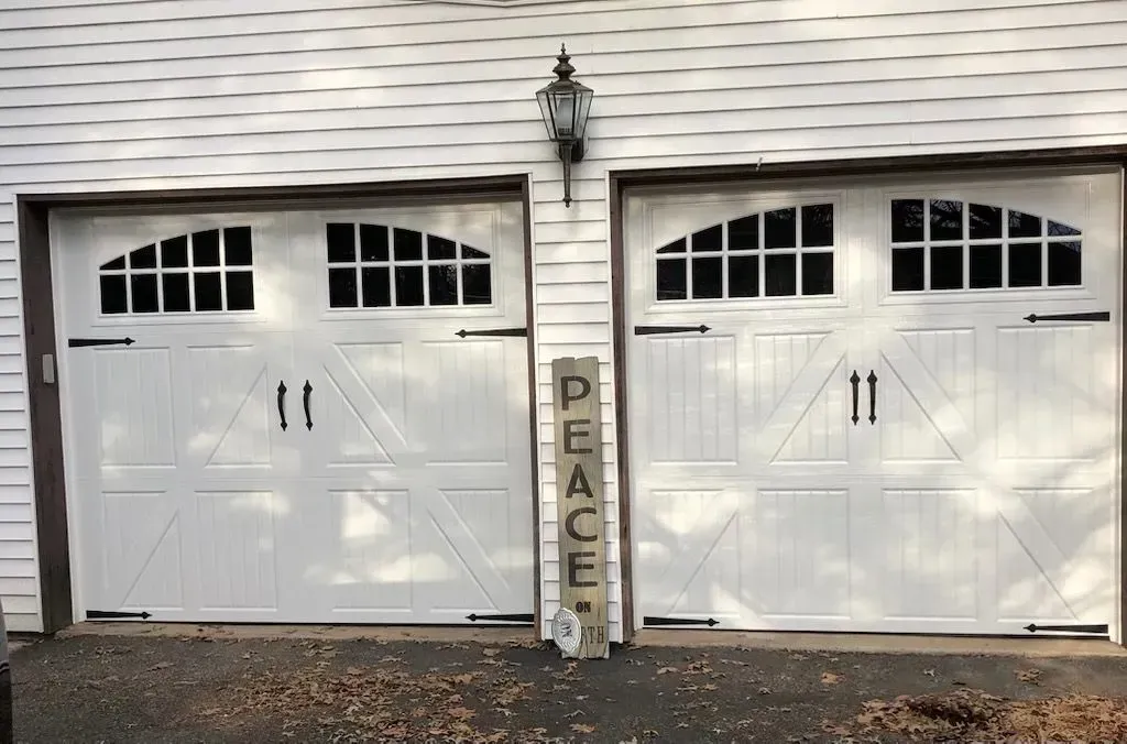 Two white garage doors with arched windows; a
