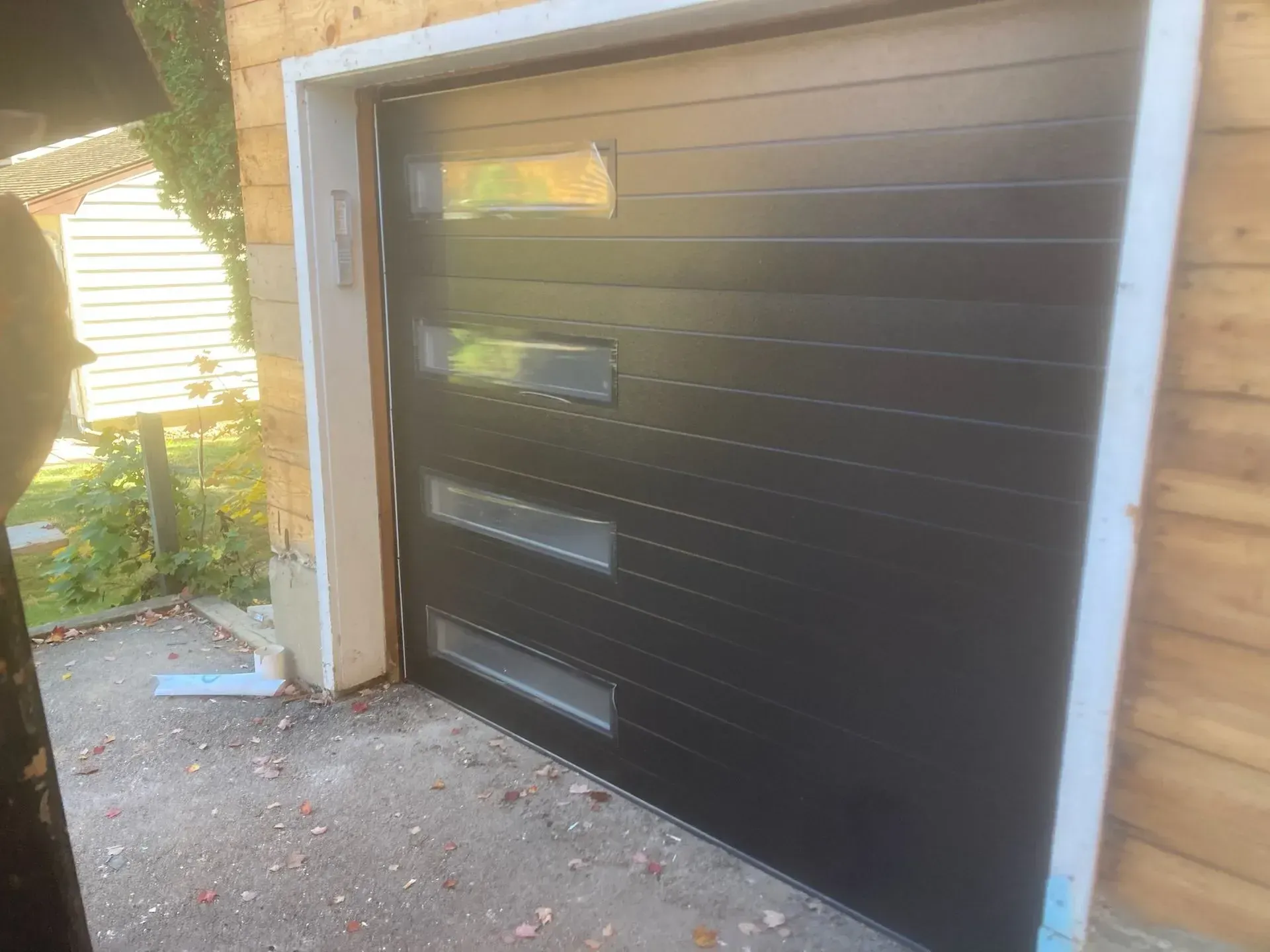 Black garage door with rectangular windows, set in a light-colored frame.