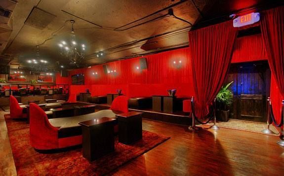 A large room with red curtains and a red exit sign.