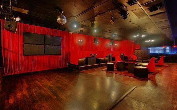 A large empty room with red curtains and a dance floor.
