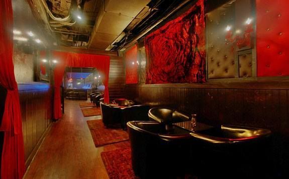 A long hallway with red curtains and chairs in a room.